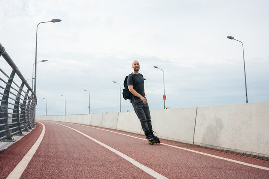 Young man inline skating on bridge against cloudy sky in city