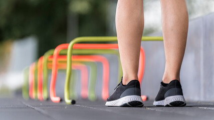 Legs of young woman standing by small hurdle