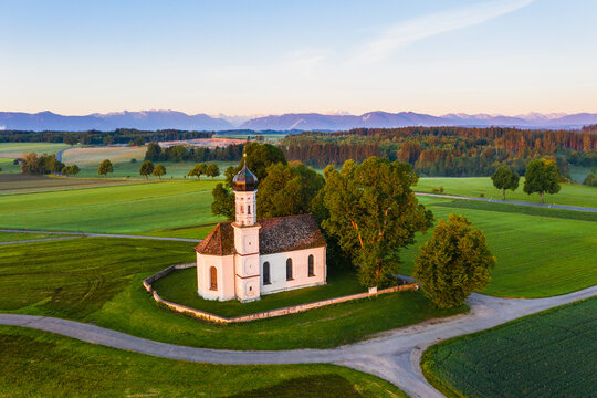 Germany, Bavaria, Etting, Drone view of Saint Andrew church surrounded by green fields at dawn