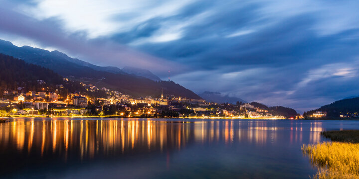 Switzerland, Canton of Grisons, Saint Moritz, panorama of Lake Saint Moritz and illuminated town in Engadine valley at dusk