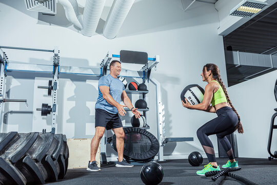 Male and female athletes exercising with medicine ball in gym