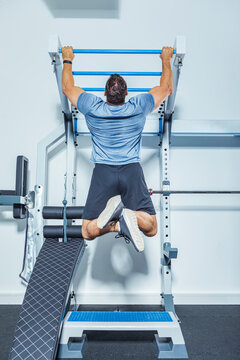 Male athlete exercising on chin-ups bars in gym