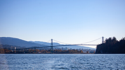 A view of North Vancouver, Stanley Park, and the Lion's Gate Bridge in British-Columbia, Canada. View taken from a sailboat leaving the harbor.