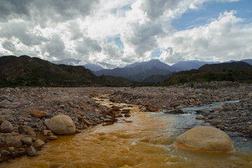 Geology. The popular Yellow River in Chilecito, La Rioja, Argentina. View of the yellow and blue river confluence, flowing along the rocky valley in the mountains in a summer day. 