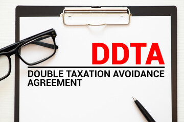Paper with DTAA Double taxation avoidance agreement on the office table, calculator and money