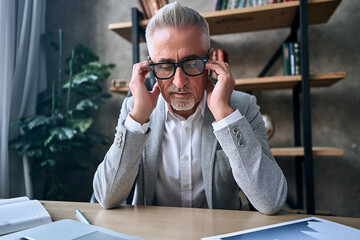 Exhausted mature man keeping eyes closed at his workplace