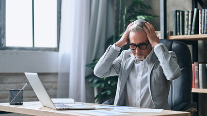 Fototapeta premium Mature gray-haired businessman having stress in the office