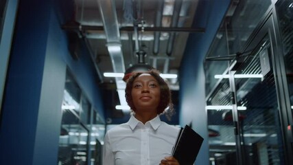 Smiling afro woman waving hand in corridor. Friendly businesswoman saying hi - Powered by Adobe