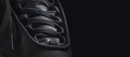 Black sneaker shoe on a black background. Closeup