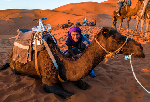 Happy tourist posing for a photo with a dromedary