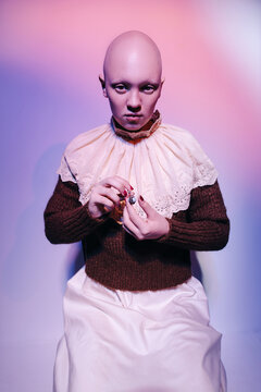 Young hairless model in vintage earrings and jabot