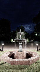 Obraz premium Fountain in the square in the night city park.