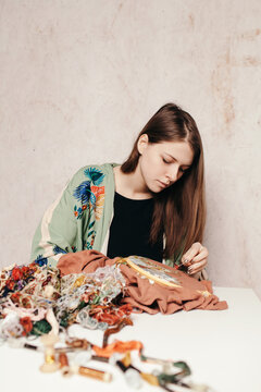 Focused woman working with embroidery at messy table