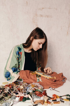 Focused woman working with embroidery at messy table
