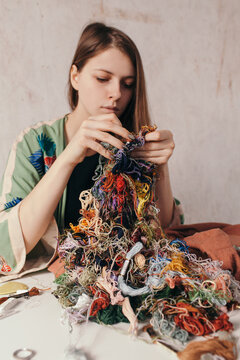 Focused woman working with embroidery at messy table