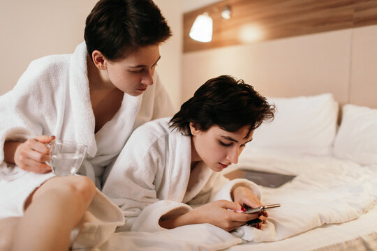 Lesbian couple resting on bed after bath