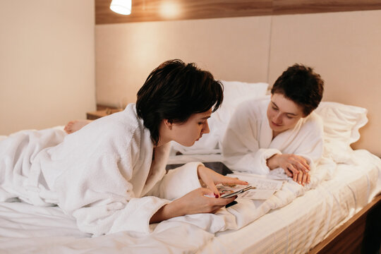 Lesbian couple making order on hotel bed