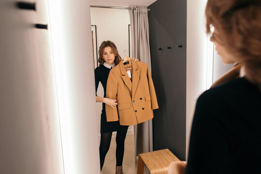 Young Woman Looking At A Blazer In The Mirror While Shopping