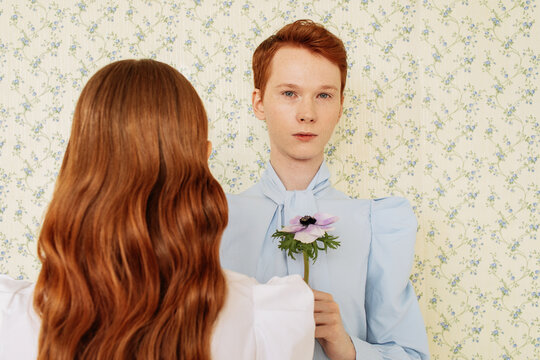 Ginger man giving flower to woman