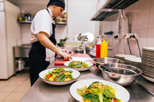 Female cook preparing salad in kitchen