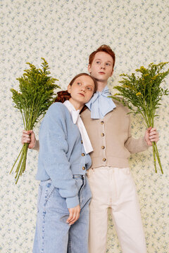 Young couple with fresh flowers against floral wall