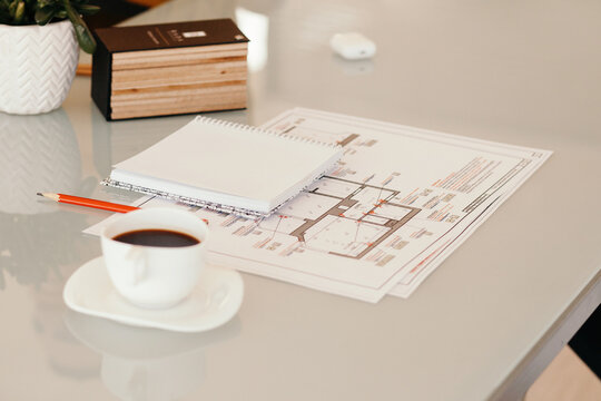 Coffee and notebook near drafts on table