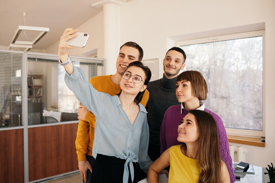 Happy colleagues taking selfie in creative workspace