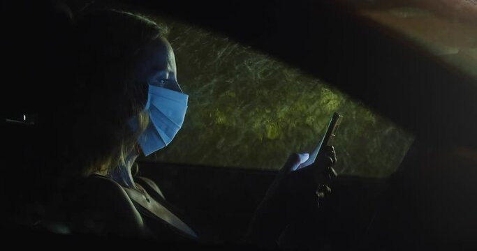 Masked woman chatting during new normal travel at night, maintaining social distance and safety, heavy rain in the big city, autumn depression and sadness