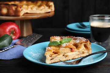 Slice of traditional apple pie served on black wooden table