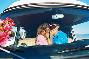 Hip couple on beach with daisies and vw van in California