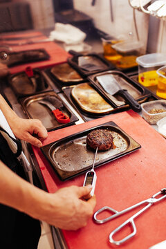 Anonymous male chef measuring temperature of patty in kitchen