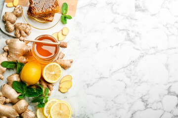 Ginger and other natural cold remedies on white marble table, flat lay. Space for text