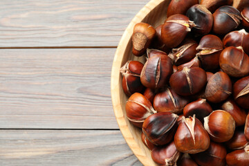 Delicious roasted edible chestnuts on wooden table, top view. Space for text
