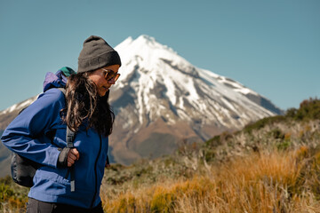 Fototapeta na wymiar Young woman walking in the mountain with snowy peak behind. Travel concept