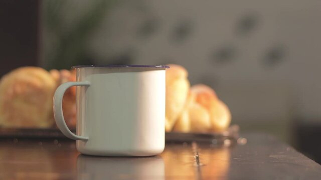 White cup with atole and bread of the dead in the background. Pan de muerto celebration in Mexico.