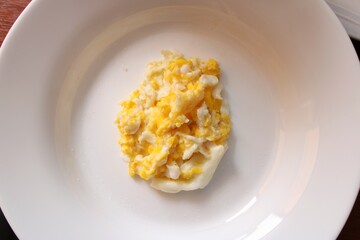 round white plate with scrambled eggs inside for early morning breakfast
