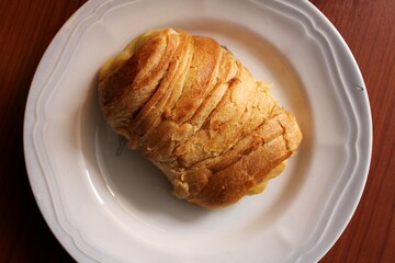 round white plate on a brown table, with a loaf inside, for an early morning breakfast
