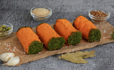 Meat rolls on a stone background.
Four meatloafs with spices, bay leaf and garlic lie diagonally on a stone background, close-up side view.