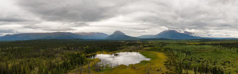 Peaceful Panoramic View of Pond and Marshland, surrounded by Forest and Mountains in Canadian Nature. Aerial Drone Shot. West of Whitehorse, East of Haines Junction, Yukon, Canada.