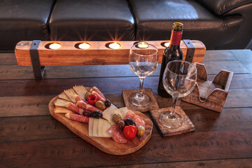 Red wine with Charcuterie board on rustic wood with candles behind a spread of prosciutto panino