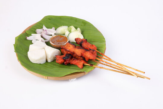Chicken beef mutton meet Satay set nasi impit sticky rice cake sliced onion cucumber sweet peanut sauce on banana leaf bamboo basket on white background
