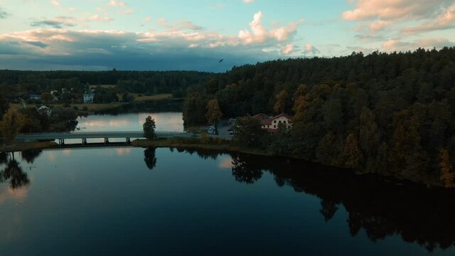 Aerial dolly shot of natural lake surrounded by forest and small village Kowalskie Blota in Poland.