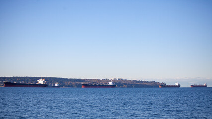 Fototapeta na wymiar Looking Vancouver's University of British-Columbia (Kitsilano and Spanish Banks) from the North Shore, the shoreline is lined with container freighter ships in British-Columbia, Canada