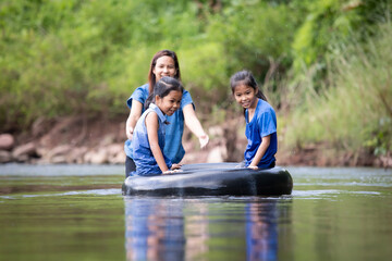 Asian mother and her daughters playing in the river together with fun and enjoy with nature.