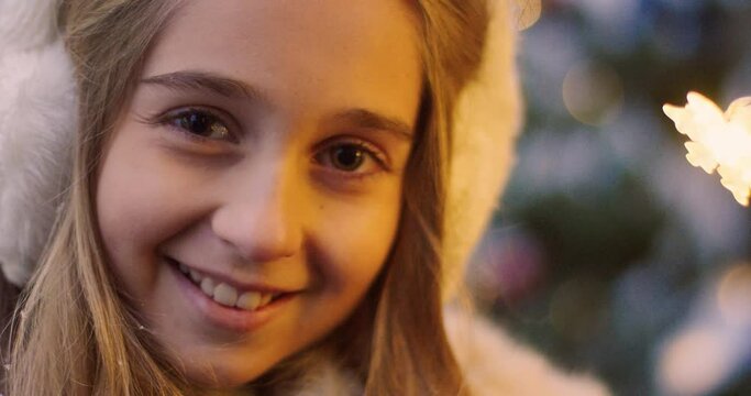 Close up portrait of beautiful blonde girl in winter headphones smiling at the camera. Winter children's vacation. Christmas mood.