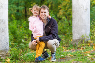 Fototapeta premium .A girl with a broken arm hugs her dad in an old park on an autumn walk
