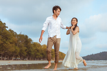Young couple holding hands and running on the beach.
