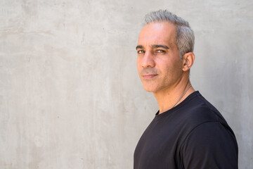 Profile view of handsome Persian man with gray hair looking at camera