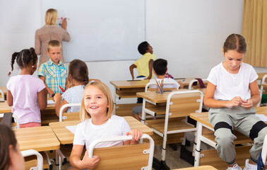 Fototapeta na wymiar Tween boys and girls friendly talking in break between lessons sitting in classroom