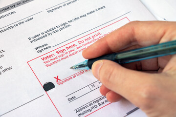 Closeup voter signing ballot envelope